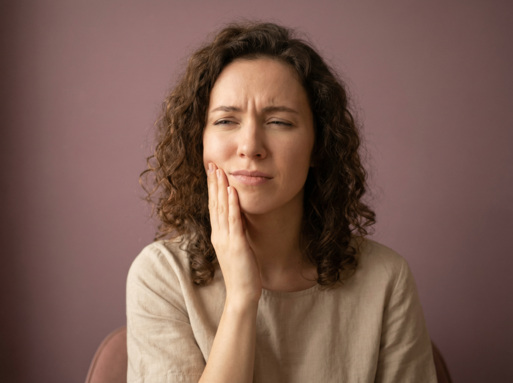 Patient experiencing wisdom tooth pain holding their jaw